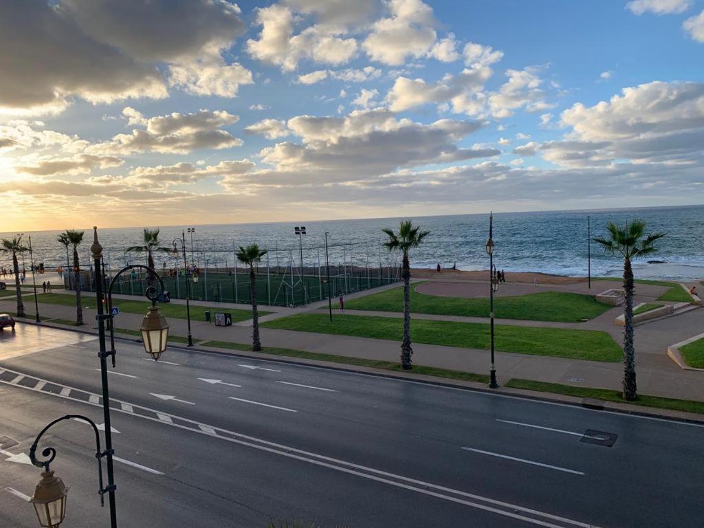 a street next to the ocean with palm trees at Appt front la mer in Rabat