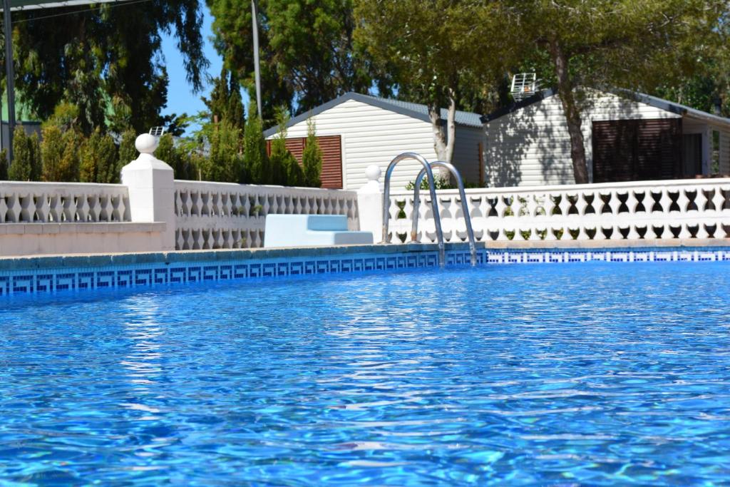 a swimming pool with a white fence and blue water at Camping Valencia el Saler in El Saler
