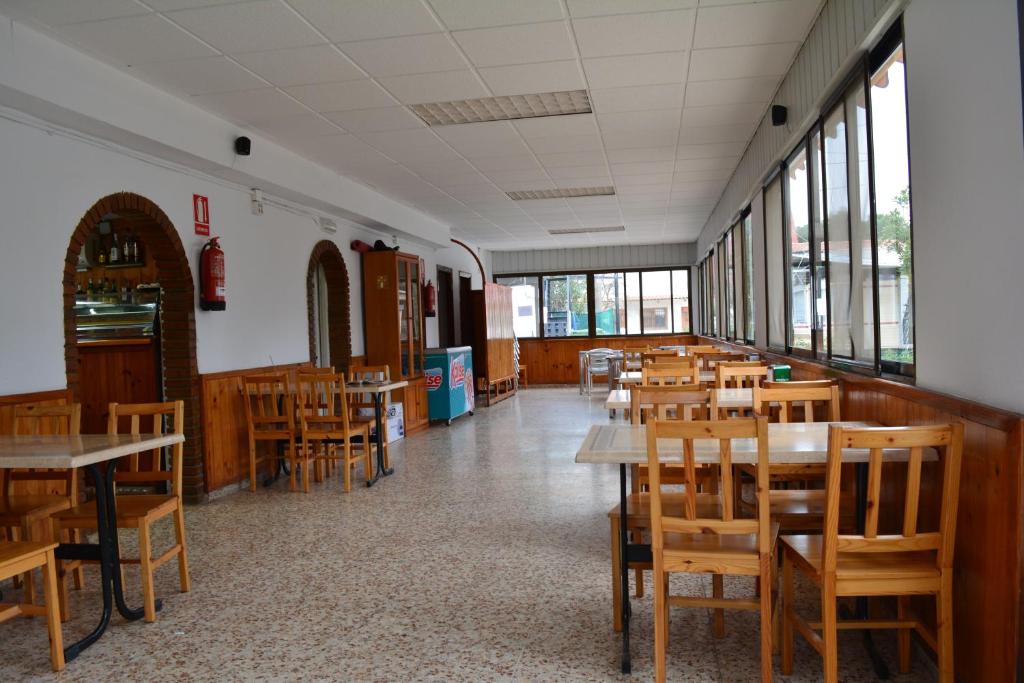 a dining room with tables and chairs and windows at Camping Valencia el Saler in El Saler