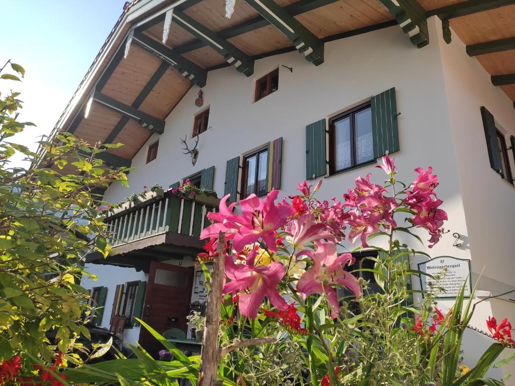 une maison avec un balcon et des fleurs roses dans l'établissement Künstlerhaus Weissgerbergütl, à Marquartstein