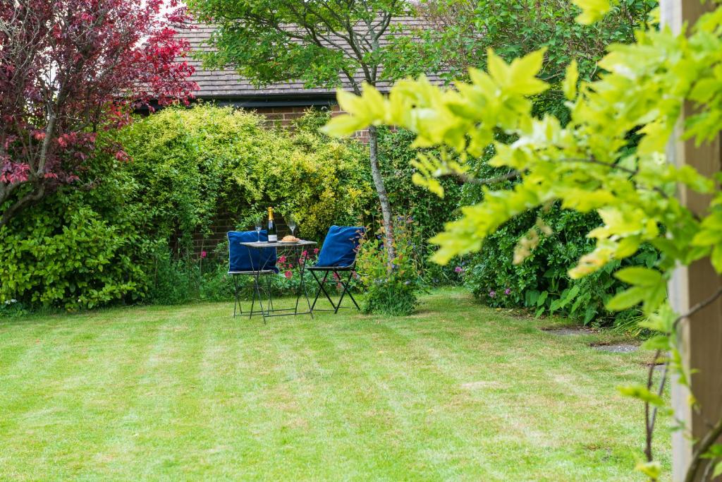 a garden with two chairs and a table in the grass at Lewes Heights is a spacious modern luxury home with stunning views in Lewes