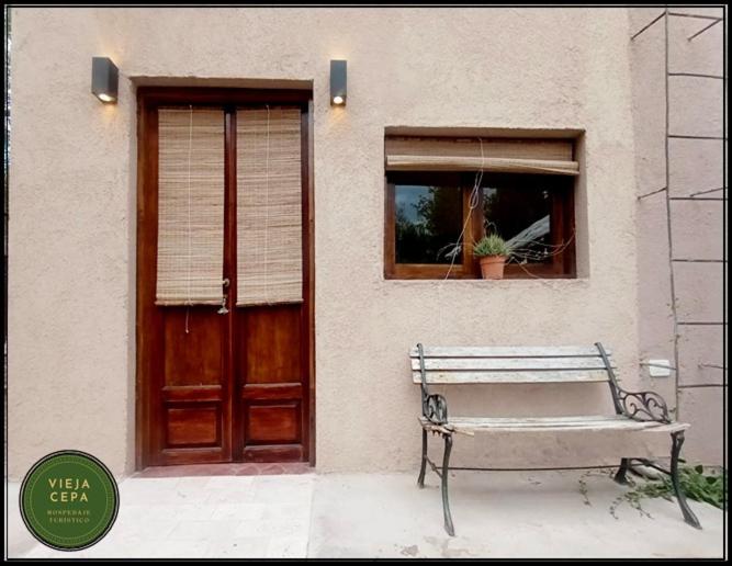 un banco sentado frente a un edificio con una puerta en Vieja Cepa Departamento en San Rafael