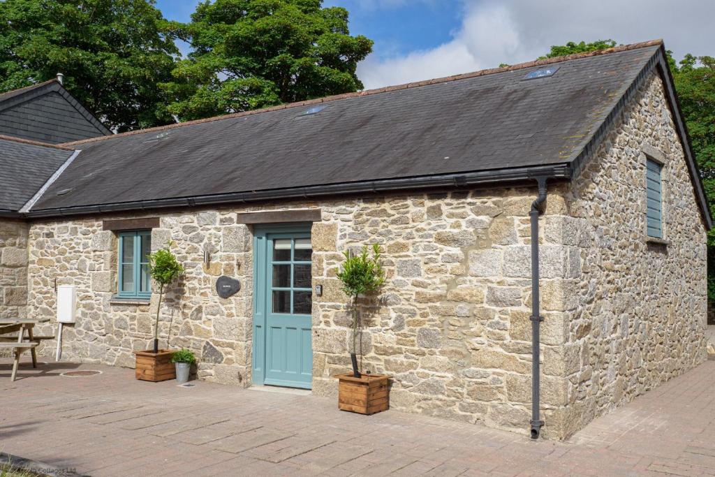 un edificio de piedra con una puerta azul en Budock Cottage en Mawnan
