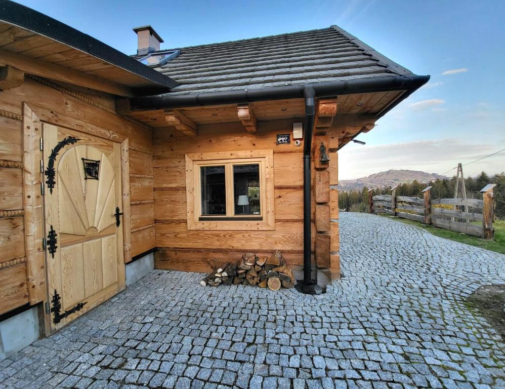 a wooden cabin with a door on a stone driveway at Wheelchair With Wings in Jaworzynka