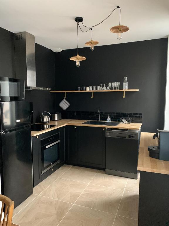 a kitchen with black cabinets and a black wall at Champagne! Appartement spacieux Reims centre in Reims