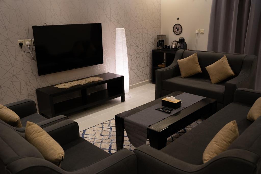 sala de estar con sofás y TV de pantalla plana. en Fans Hotel Suites en Abha
