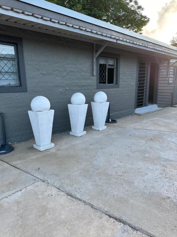 three white vases sitting on the side of a house at One Home in Pretoria