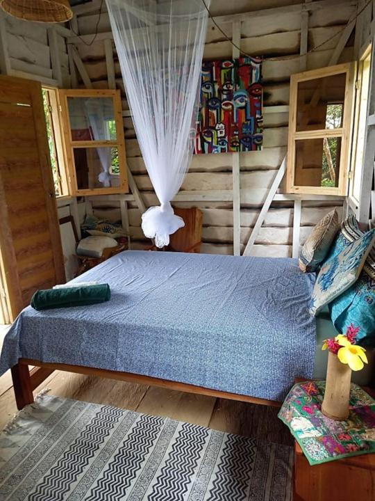 a bedroom with a bed in a log cabin at World's View Wild Camping Salaszoi, Principe Island in Santo António