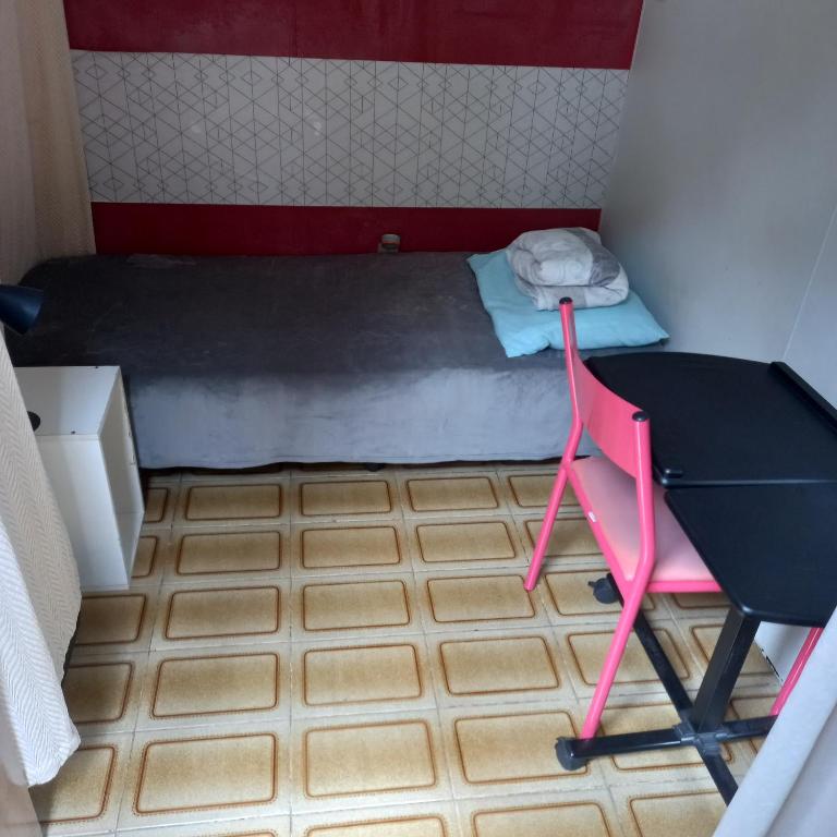 um pequeno quarto com uma cama, uma secretária e uma cadeira em Espaço Cápsula em Brasília