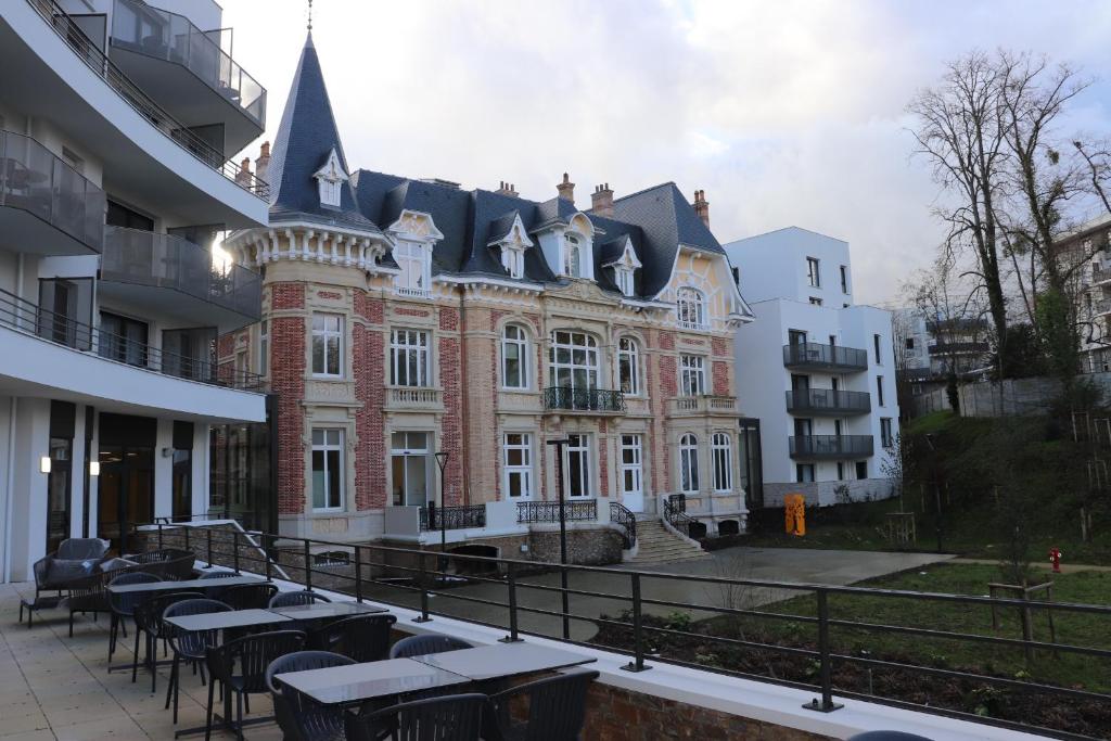 un grande edificio in mattoni con tavoli di fronte di DOMITYS LE PARC DES AUBIERS a Poissy