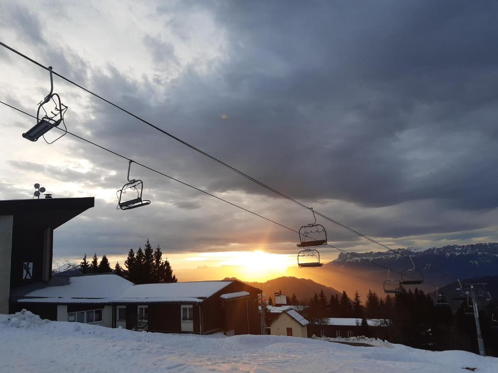 a ski lift with the sun setting in the background at Family apartment on the skiing slope in Allevard