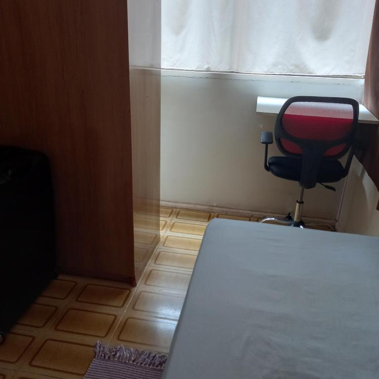 Habitación con escritorio, silla y ventana. en Vaga em quarto em Brasília en Brasilia