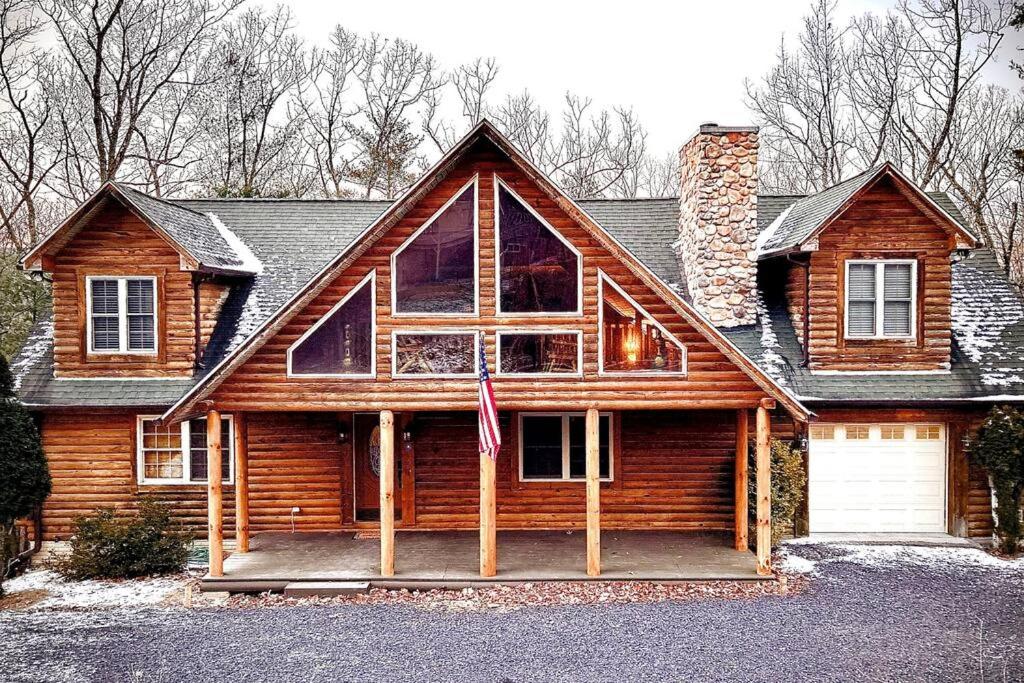 ein Holzhaus mit einer Flagge davor in der Unterkunft One of a Kind Rustic Log Cabin near Bryce Resort - Large Game Room - Fire Pit - Large Deck - BBQ in Basye