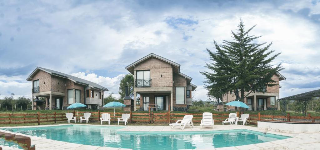 una casa con piscina con sillas y sombrillas en Pentagrama, casas de campo en Villa General Belgrano