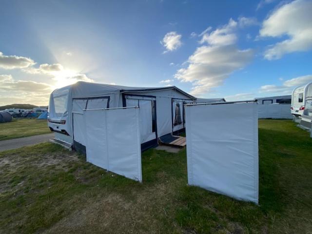 una caravana estacionada en un campo con dos puertas blancas en Wohnwagenvermietung Sylt, en Rantum