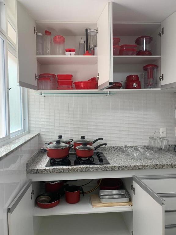a kitchen with red pots and pans on a stove at Apartamento Prainha Arraial in Arraial do Cabo