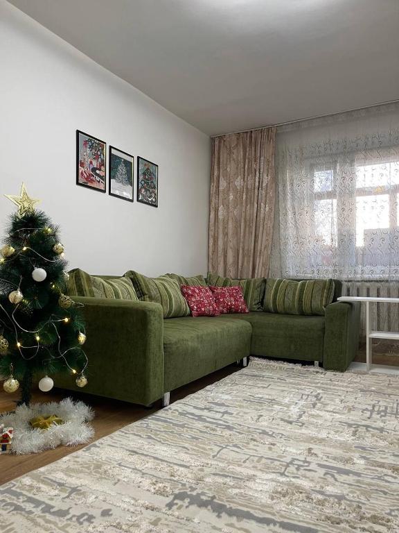 uma sala de estar com um sofá verde e uma árvore de Natal em Дизайнерская трехкомнатная квартира em Karaganda