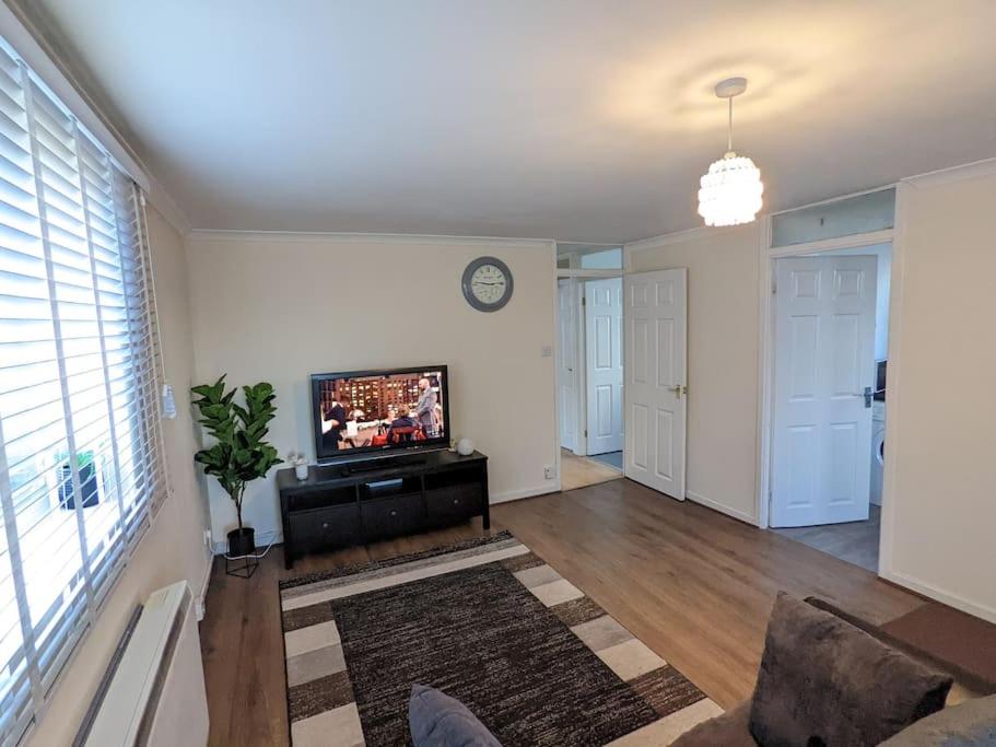 a living room with a tv and a couch and a clock at LTK Basildon in Nevendon