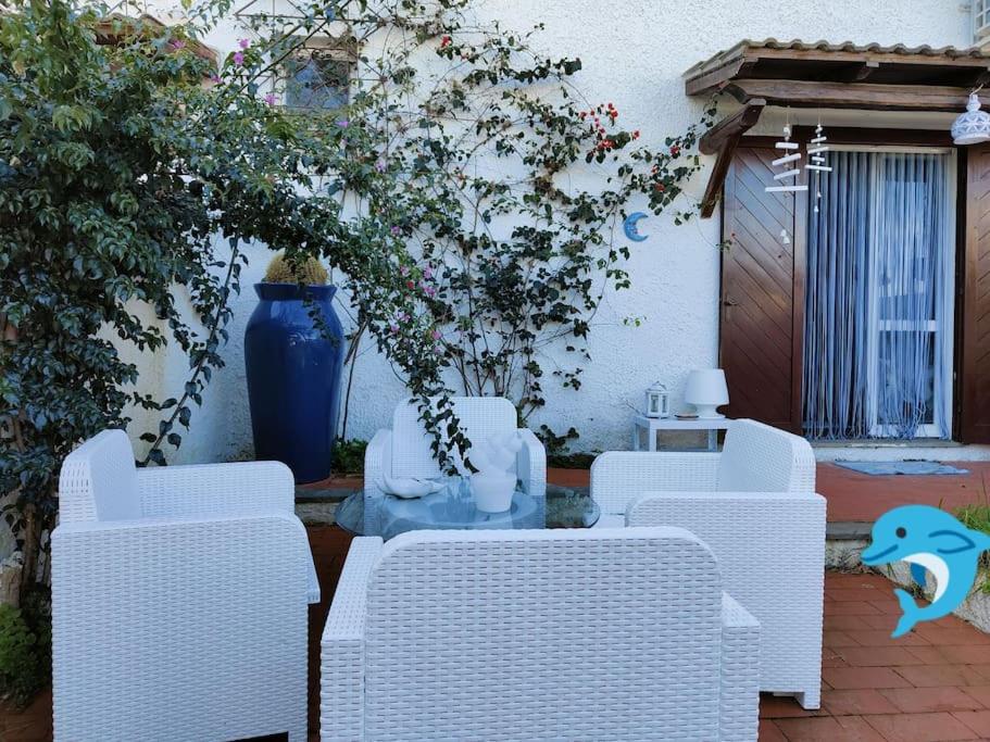 un patio con sillas blancas y un jarrón azul en Ridente villetta a schiera, 10min a piedi dal mare, en San Felice Circeo