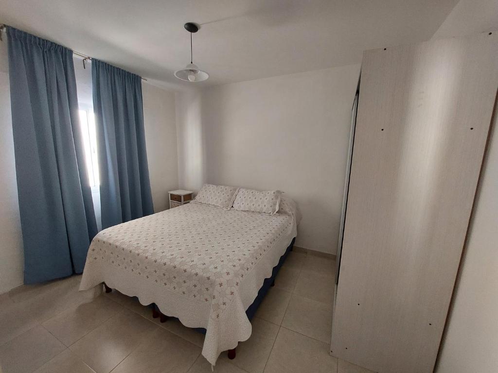 a small bedroom with a bed and blue curtains at Departamento centro in San Luis