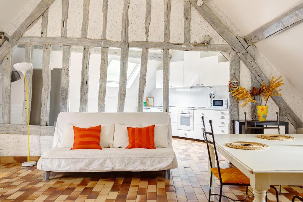 a living room with a white couch with orange pillows at Le Moulin de Dannemarie in Dannemarie