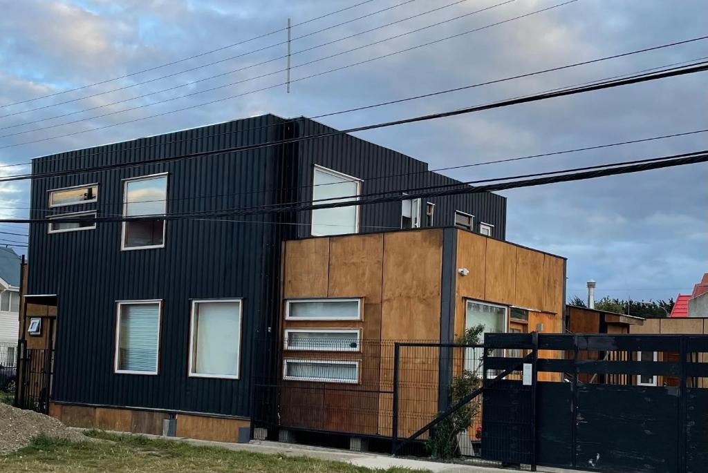 a black house with white windows on a street at Espacio Innata in Punta Arenas