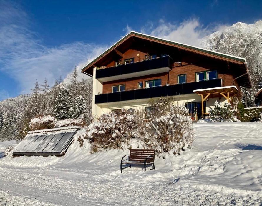 a bench in the snow in front of a building at Haus Werner in Ramsau am Dachstein