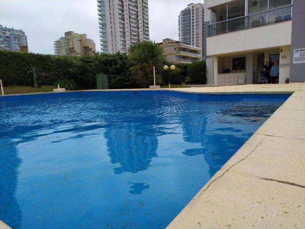 a large blue swimming pool with buildings in the background at Cap Breton - PentHouse in Punta del Este