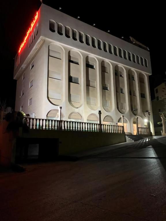 a white building with a red sign on it at Nojoom Hotel in Amman