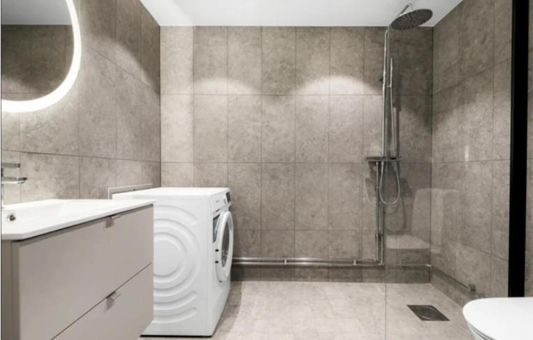 a bathroom with a washing machine and a shower at Solna Property Apartment in Stockholm
