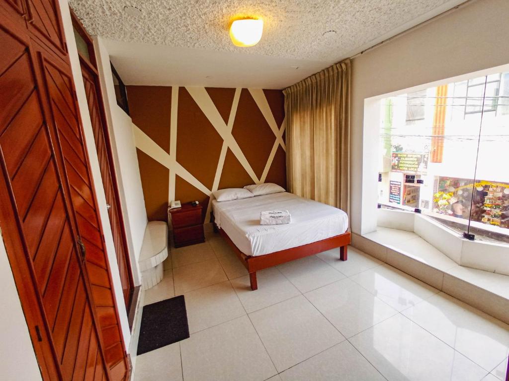 um pequeno quarto com uma cama e uma janela em Hotel Plaza Teatro em Chiclayo