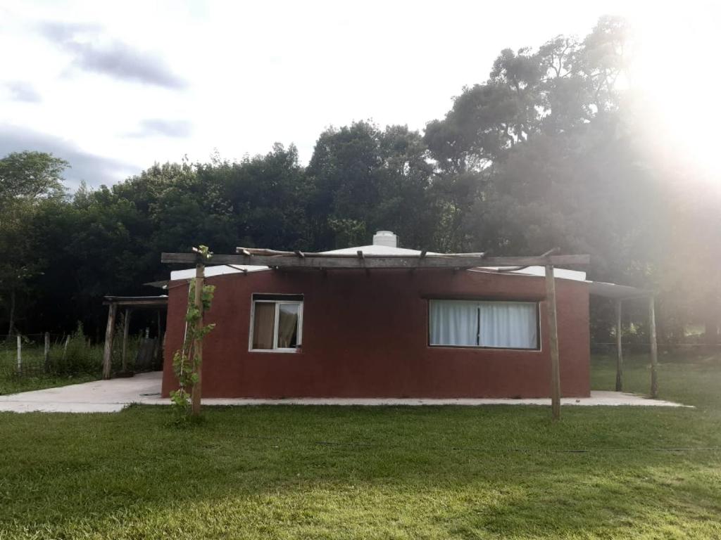 una pequeña casa roja con un patio de césped en Corralito Extremo en Rosario de Lerma
