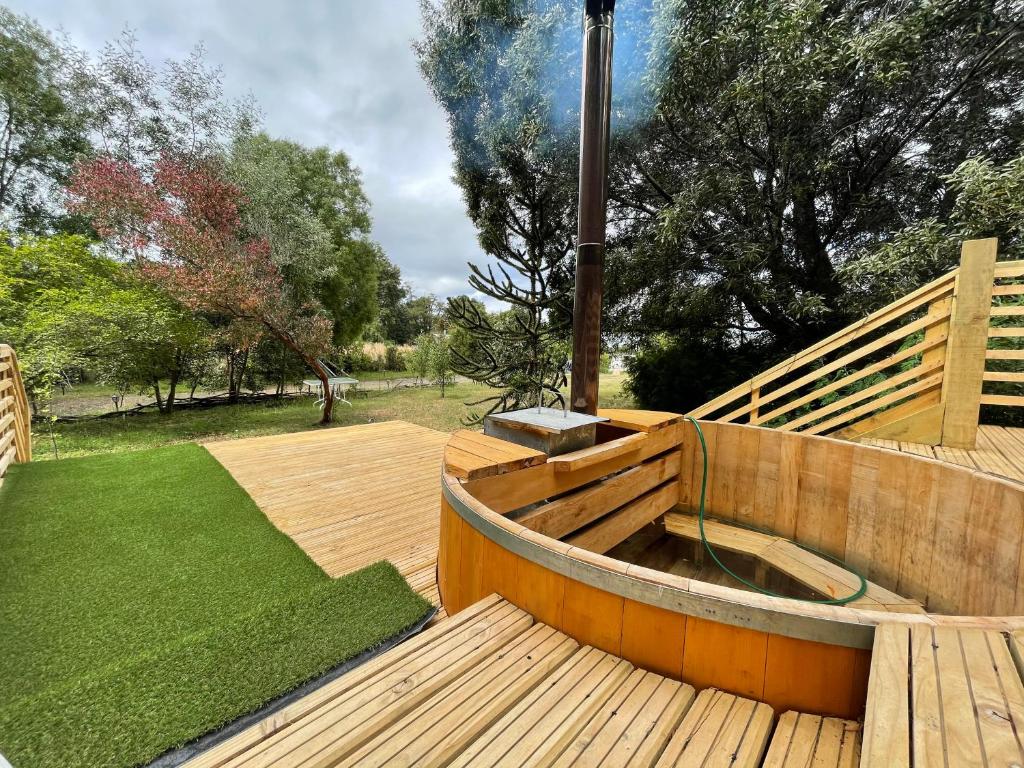 a wooden deck with a hot tub and a lawn at Tiny house los zorzales in Castro