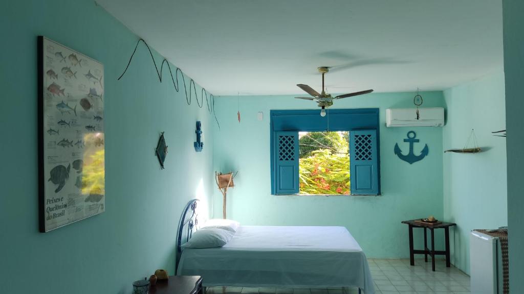 a blue bedroom with a bed and a window at A Pousada. in Barra dos Coqueiros