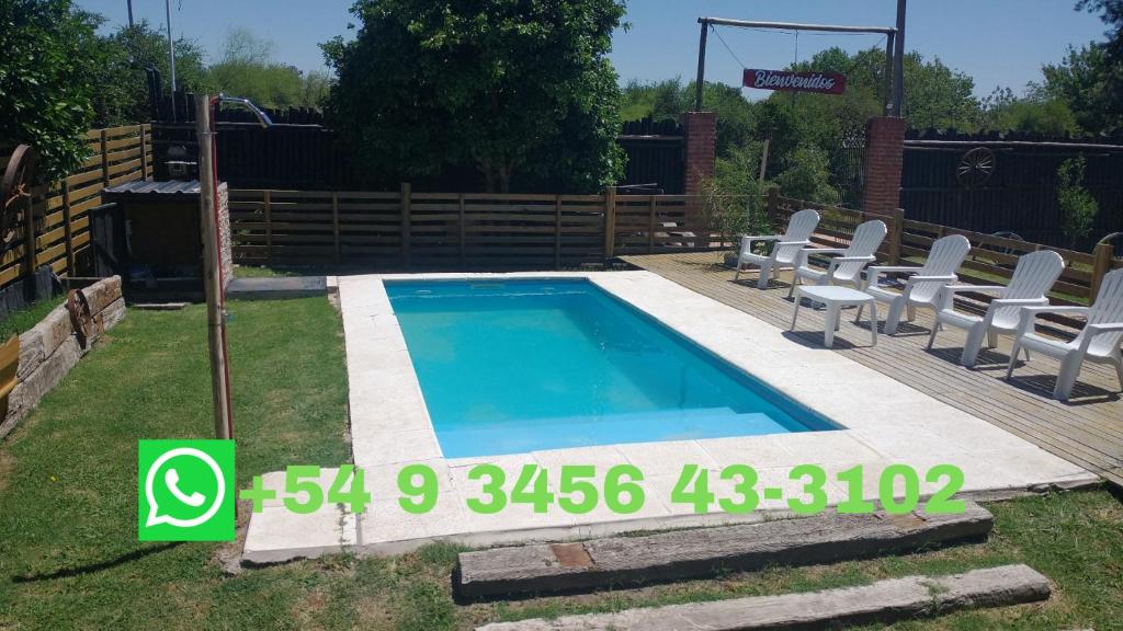 a swimming pool with chairs and a fence at Casa de Campo, con Pileta y Asador Criollo!! - "La Ranchada" in Gualeguaychú