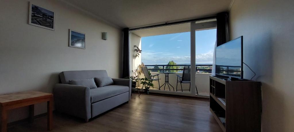 uma sala de estar com um sofá, uma televisão e uma varanda em Ainil Apartment em Valdivia