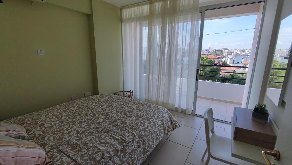 een slaapkamer met een bed en een groot raam bij Pentadaktylos Mountain view apt 2 bedroom in Nicosia