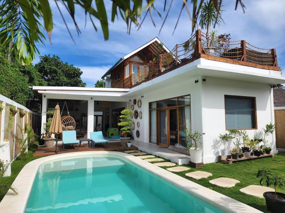 a villa with a swimming pool in front of a house at Rumah Tara Modern 3 bedroom pool and garden villa in Gili Air in Gili Islands