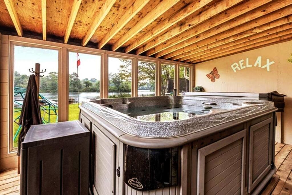 uma grande casa de banho com uma grande banheira num quarto com janelas em Pines Bay Waterfront cottage with Hot tub! em Kawartha Lakes