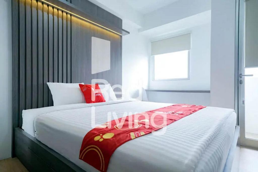 ein Schlafzimmer mit einem großen weißen Bett mit einer roten Decke in der Unterkunft RedLiving Apartemen Gunung Putri Square - Sansan Room in Parungtandjung