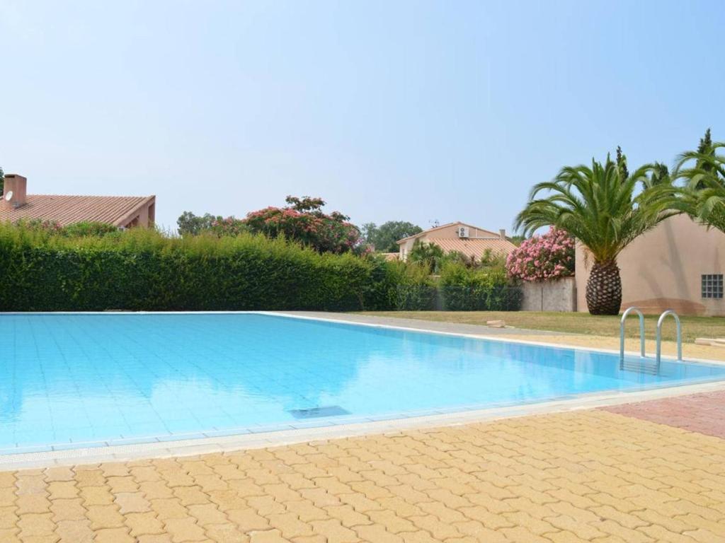 une grande piscine bleue dans une cour avec des palmiers dans l'établissement Appartement Saint-Cyprien, 2 pièces, 4 personnes - FR-1-225D-227, à Saint Cyprien Plage