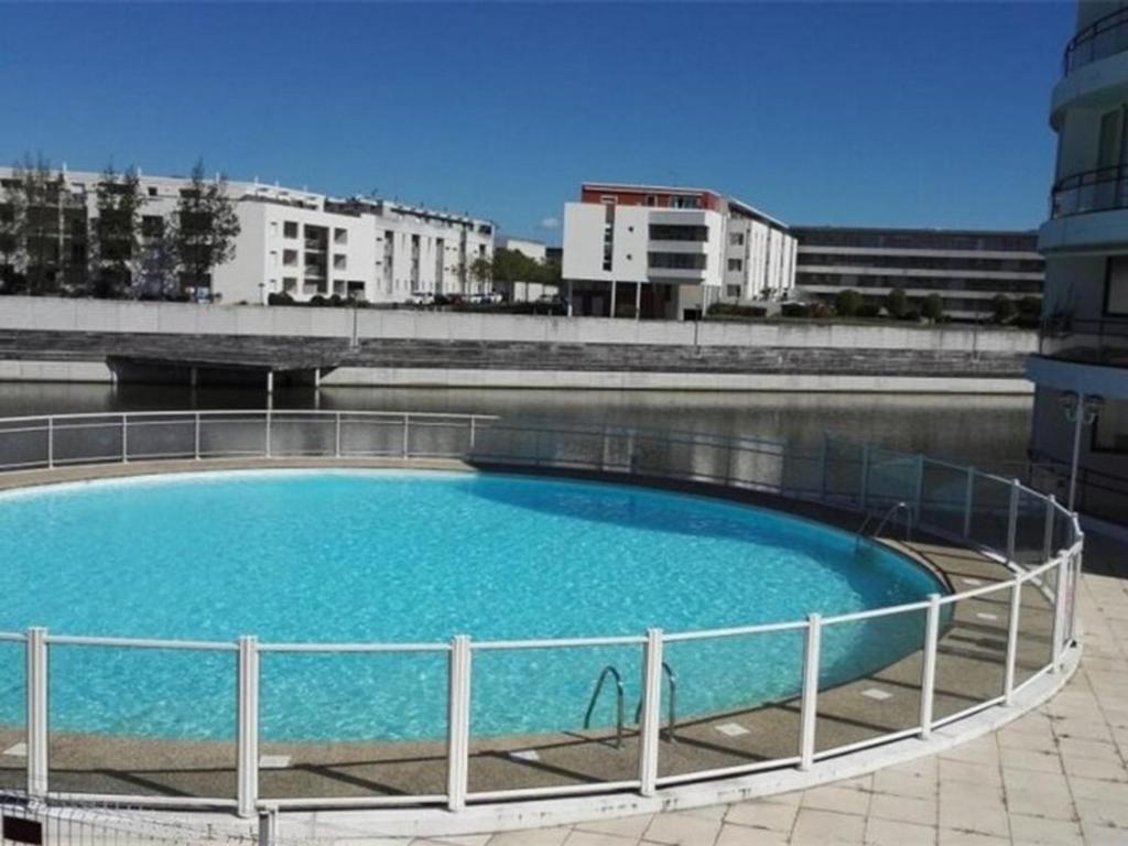 un grand bassin d'eau avec des bâtiments en arrière-plan dans l'établissement Appartement T2 avec balcon, parking et piscine, proche commodités - FR-1-535-32, à La Rochelle