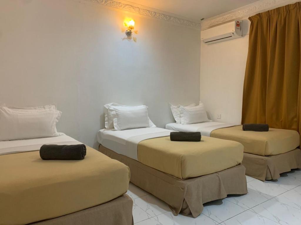 um quarto com duas camas e dois repousa-pés em ANGGERIK IMPIAN HOTEL -Best for Travellers at Kuala Berang em Kuala Berang