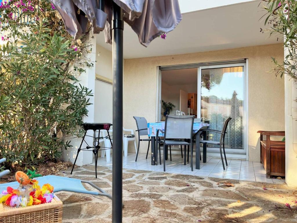 un patio avec une table, des chaises et un parasol dans l'établissement Appartement familial climatisé avec piscine, terrasse et parking - 5 couchages - Le Lavandou - FR-1-251-426, au Lavandou