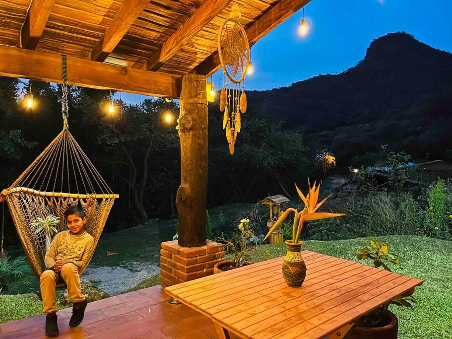 a boy sitting in a hammock under a pergola at Cabaña en Malinalco El rincón de Anita in Malinalco