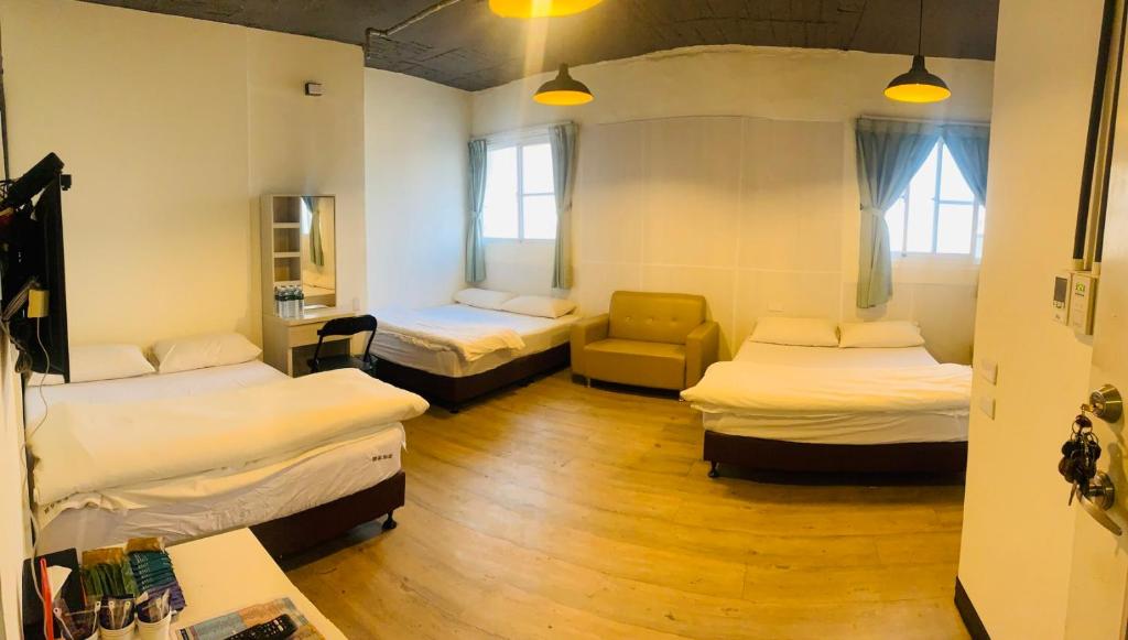 a room with three beds and a chair in it at EasyInn Hotel &amp; Hostel in Tainan