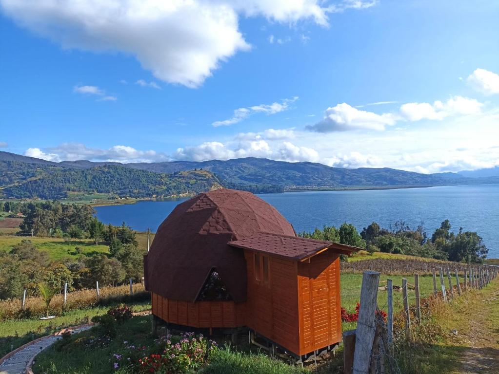 un pequeño edificio en una colina junto a un cuerpo de agua en Domos lago Muisca Xue, en Aquitania