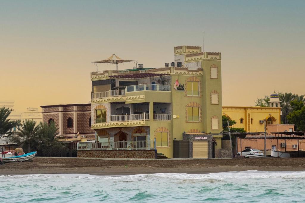 ein Gebäude am Strand neben dem Wasser in der Unterkunft Nhar Accommodation House in Suhar