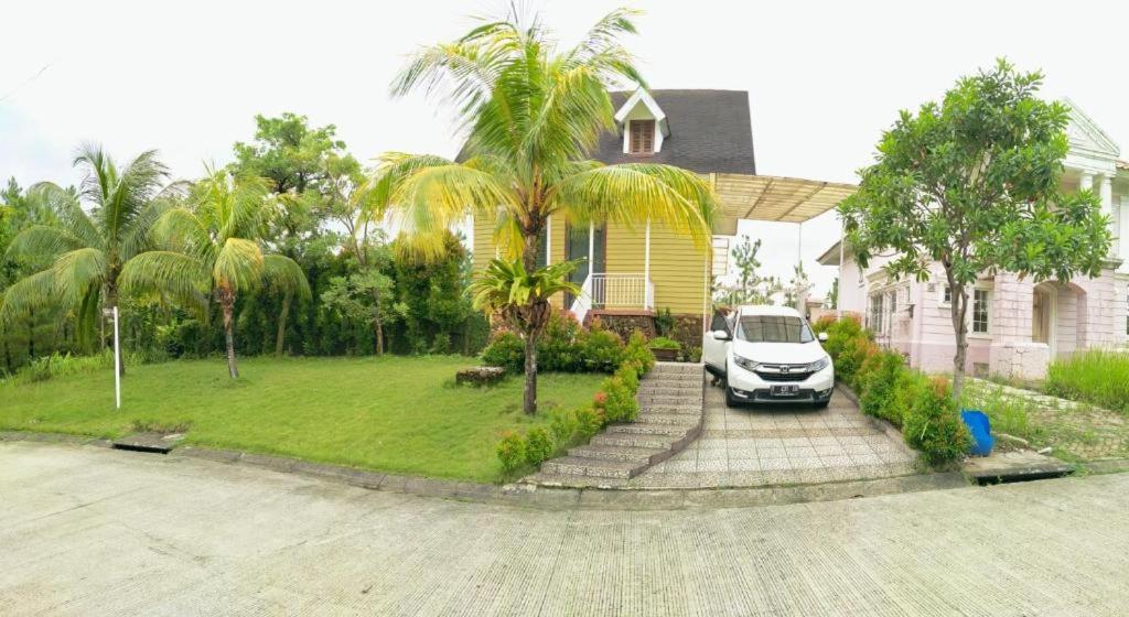 um carro estacionado em frente a uma casa com palmeiras em Villa Gathering Yuni Syahla em Citaringgul 1