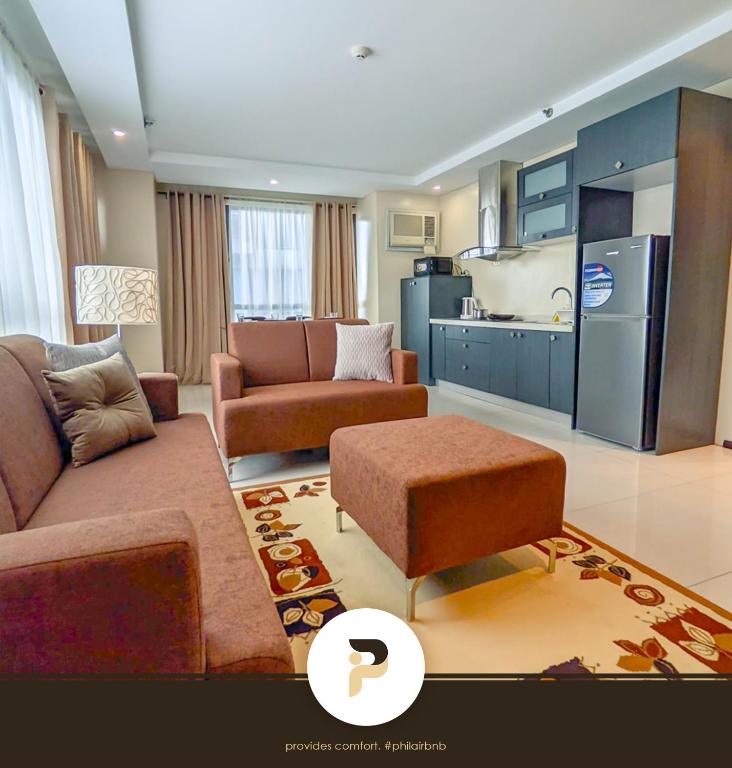 a living room with a couch and a kitchen at SPACIOUS 2BR NEAR MOA, SOLAIRE CASINO AND PASAY AREA in Manila